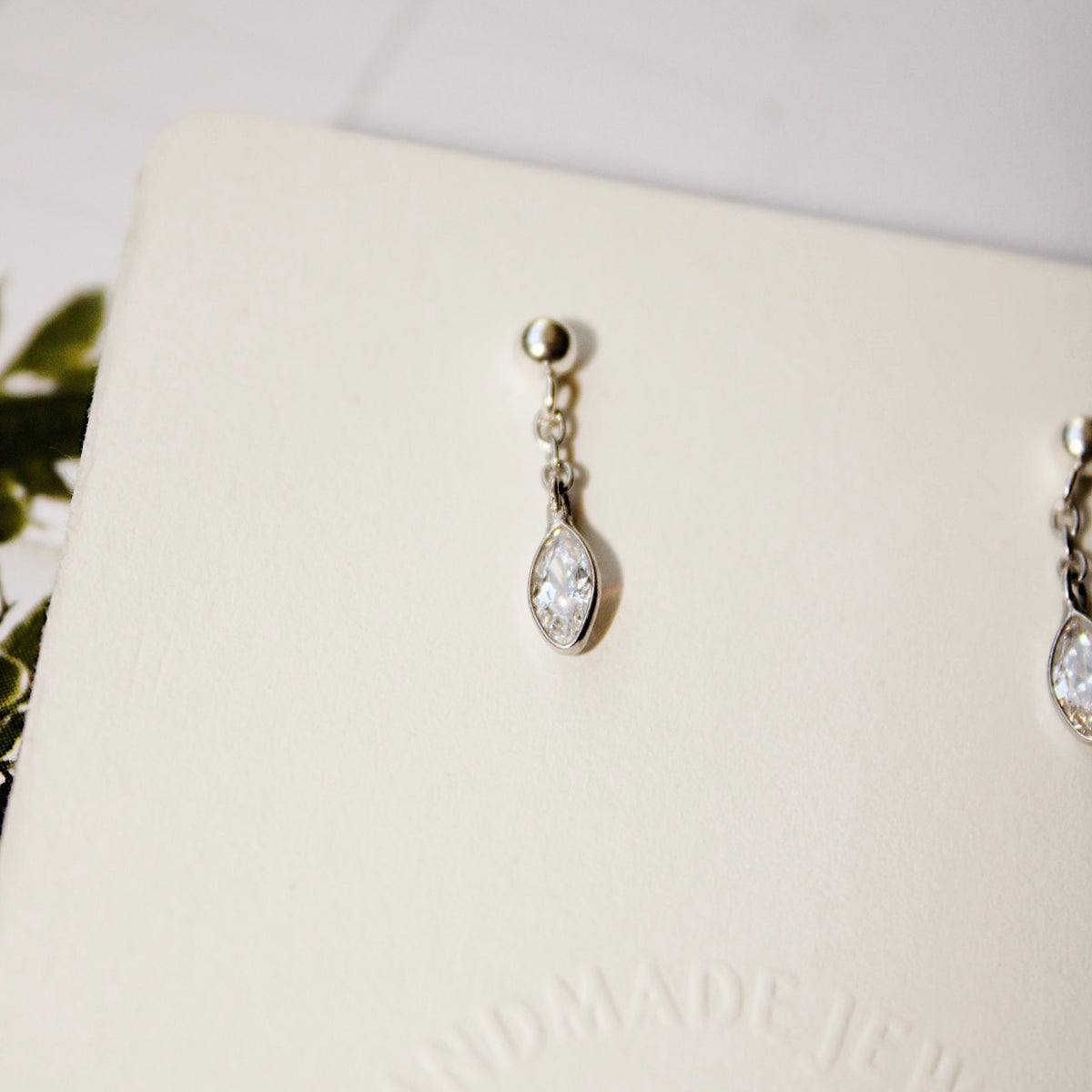 Close-up of a Dana earring showing its silver ball stud, short chain and marquise-shaped cubic zirconia charm.