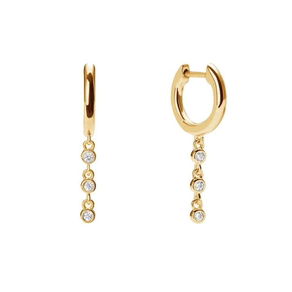 Lucy gold-plated huggie hoops with three clear cubic zirconia drops on each earring, shown from front and side on white.