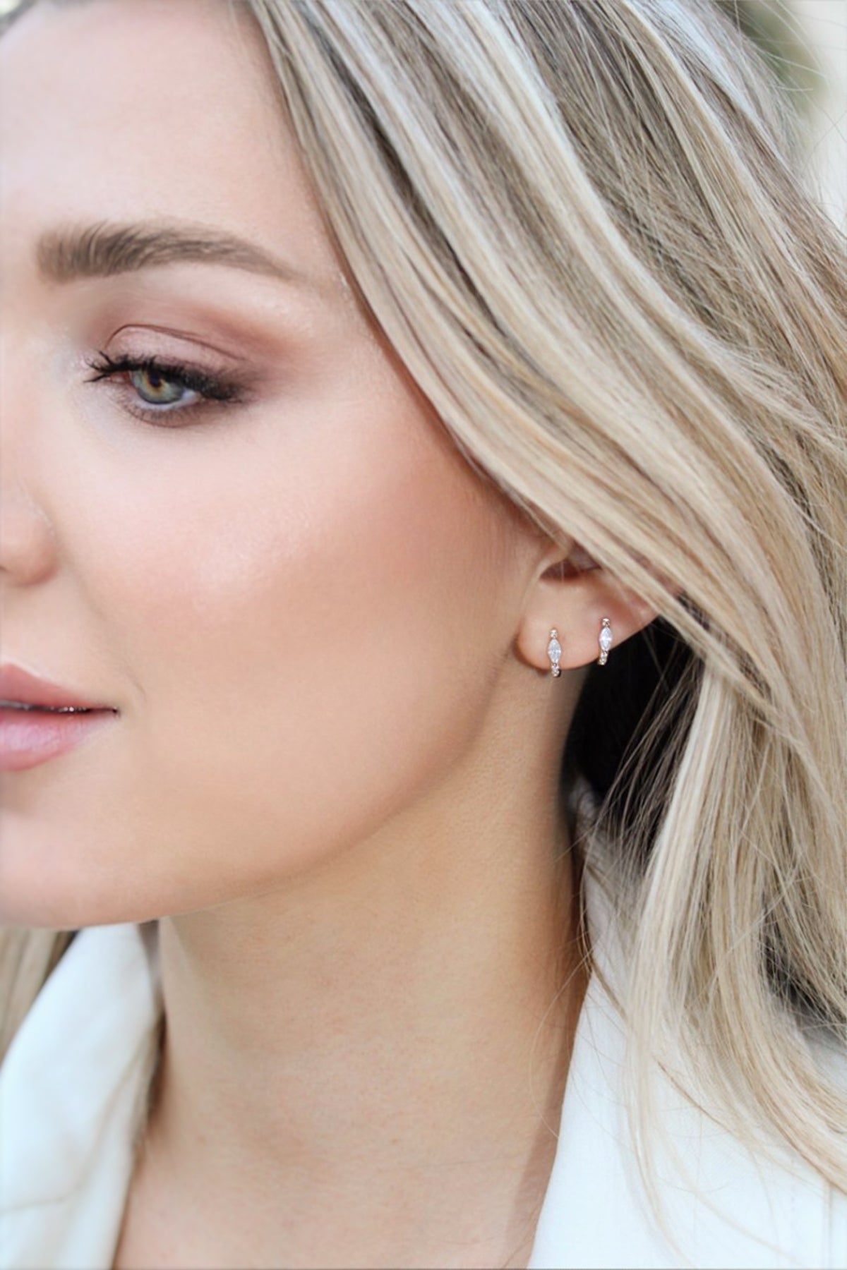 Close-up of two Landon huggies worn together in adjacent ear piercings, showing their marquise-shaped clear stones.